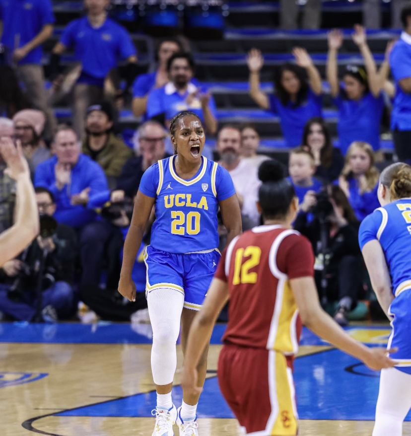 UCLA guard Charisma Osborne celebrates a basket against USC. She is wearing UCLA blue and yellow home jersey.